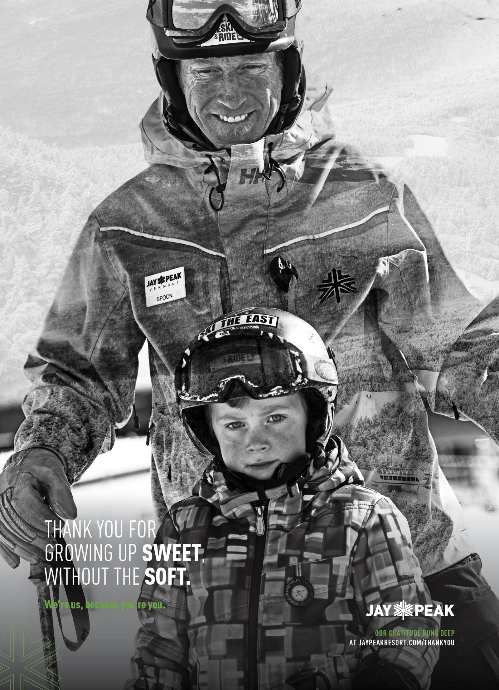 Smiling adult and child in winter gear, wearing ski helmets and goggles, in the snow.