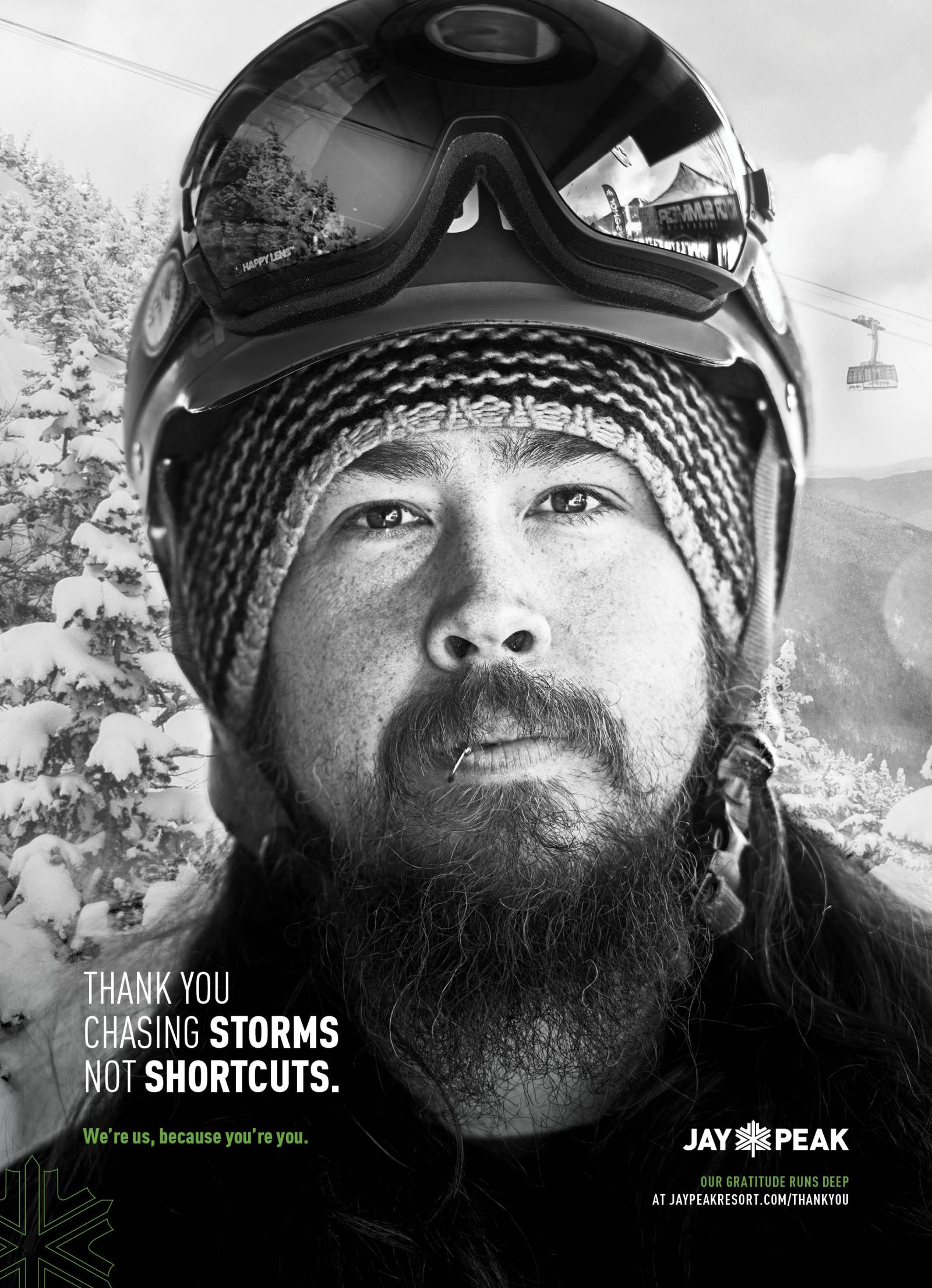 Man in winter attire with ski goggles, snowy mountain background. Black and white photo.