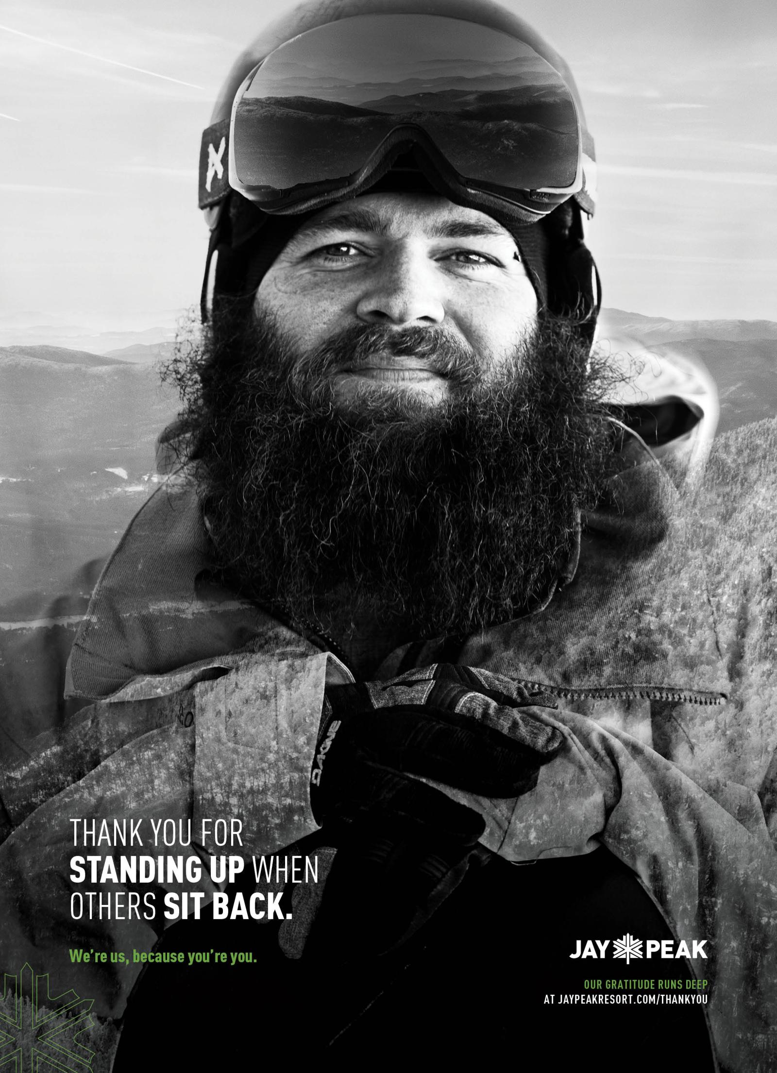 Bearded skier with goggles in snowy landscape, black and white photograph.