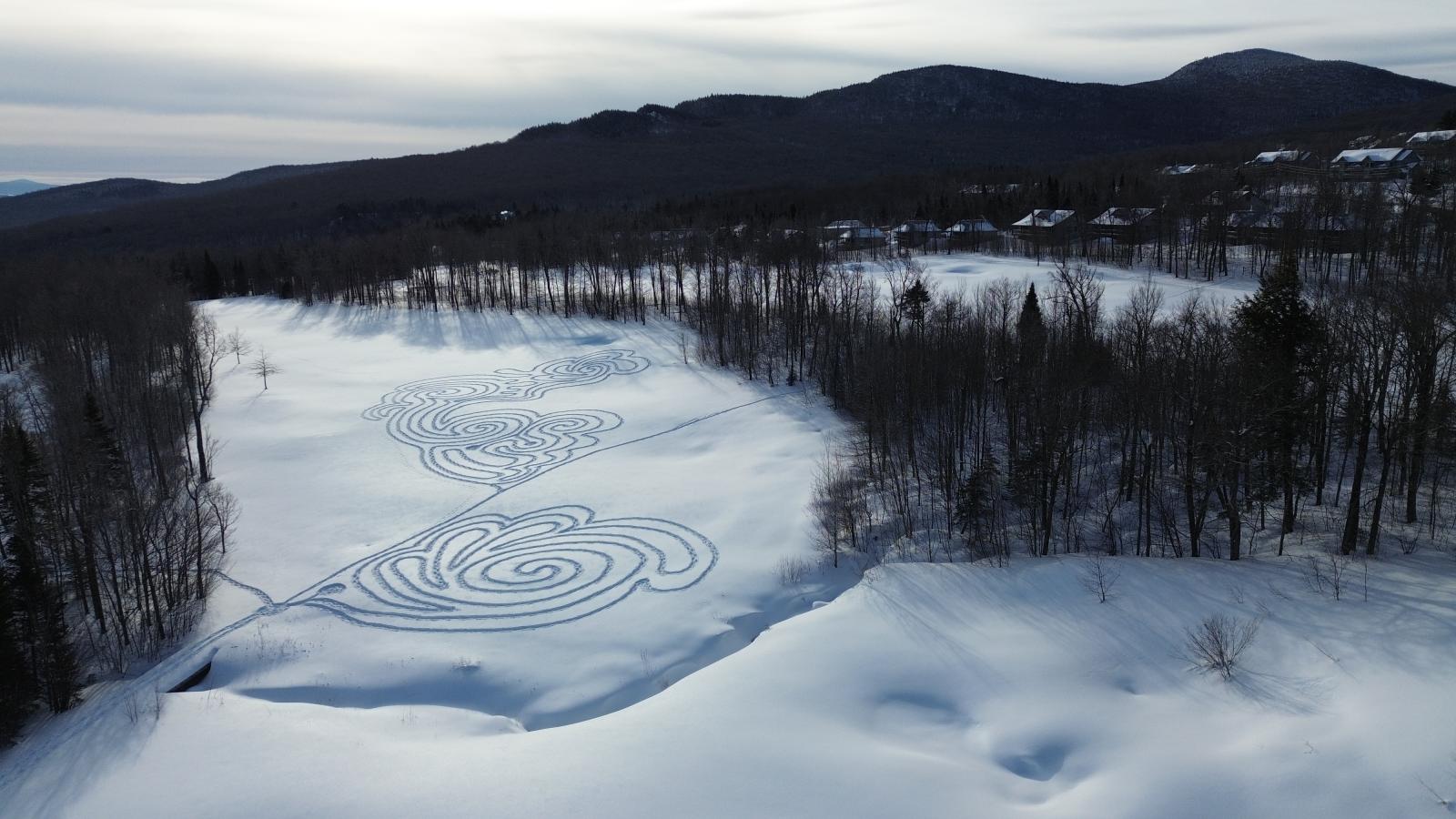 Snowy landscape with intricate snow patterns and mountains in the background.