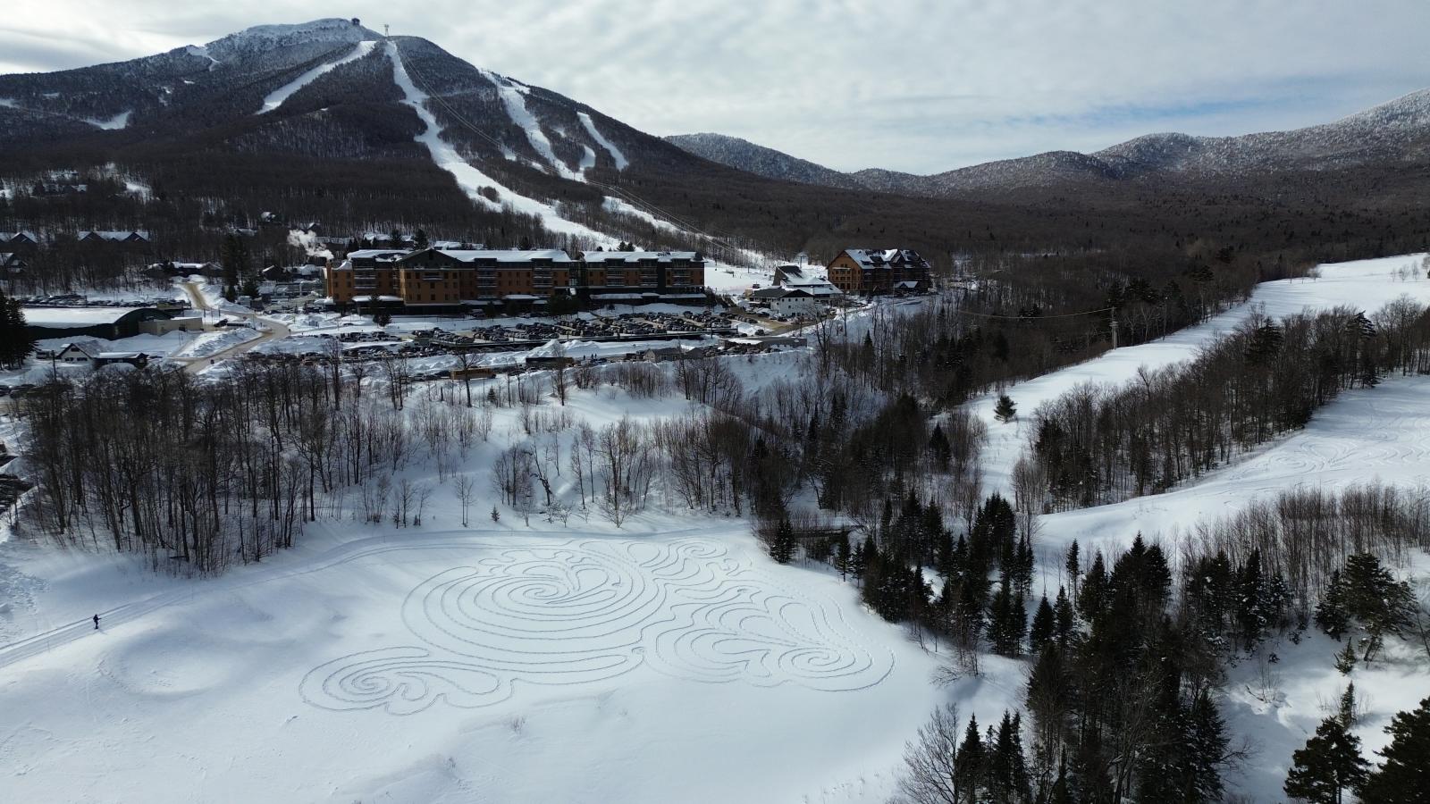Snowy mountain landscape with ski trails and forested slopes.