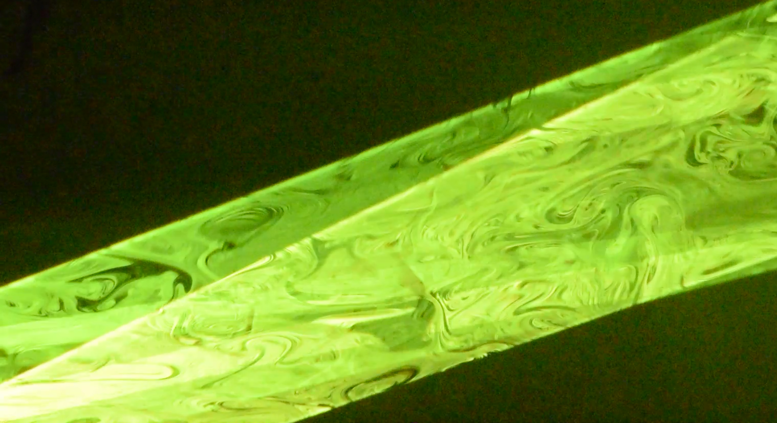 Green swirled glass sculpture on a dark background.