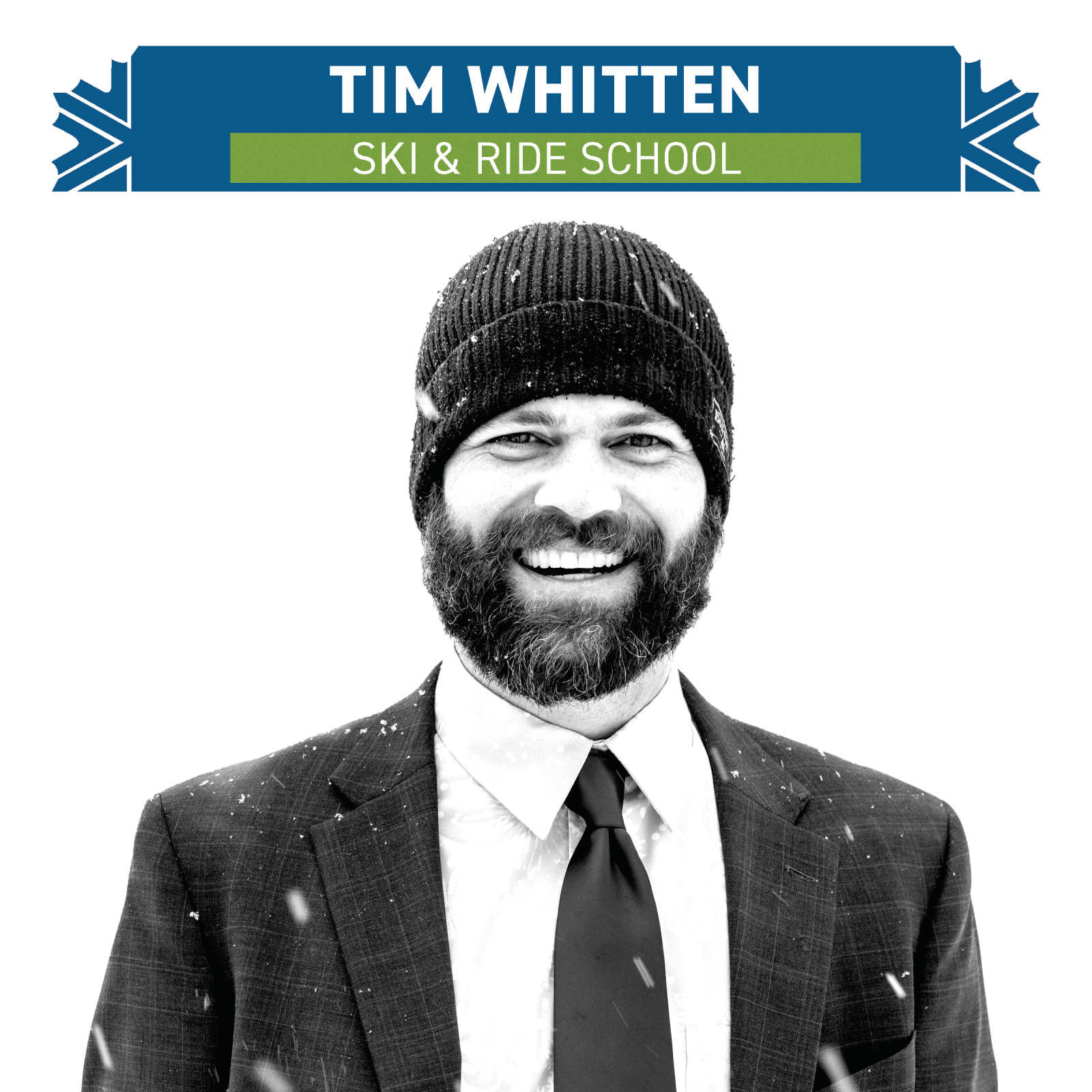Man in suit and beanie smiling, with snow falling.