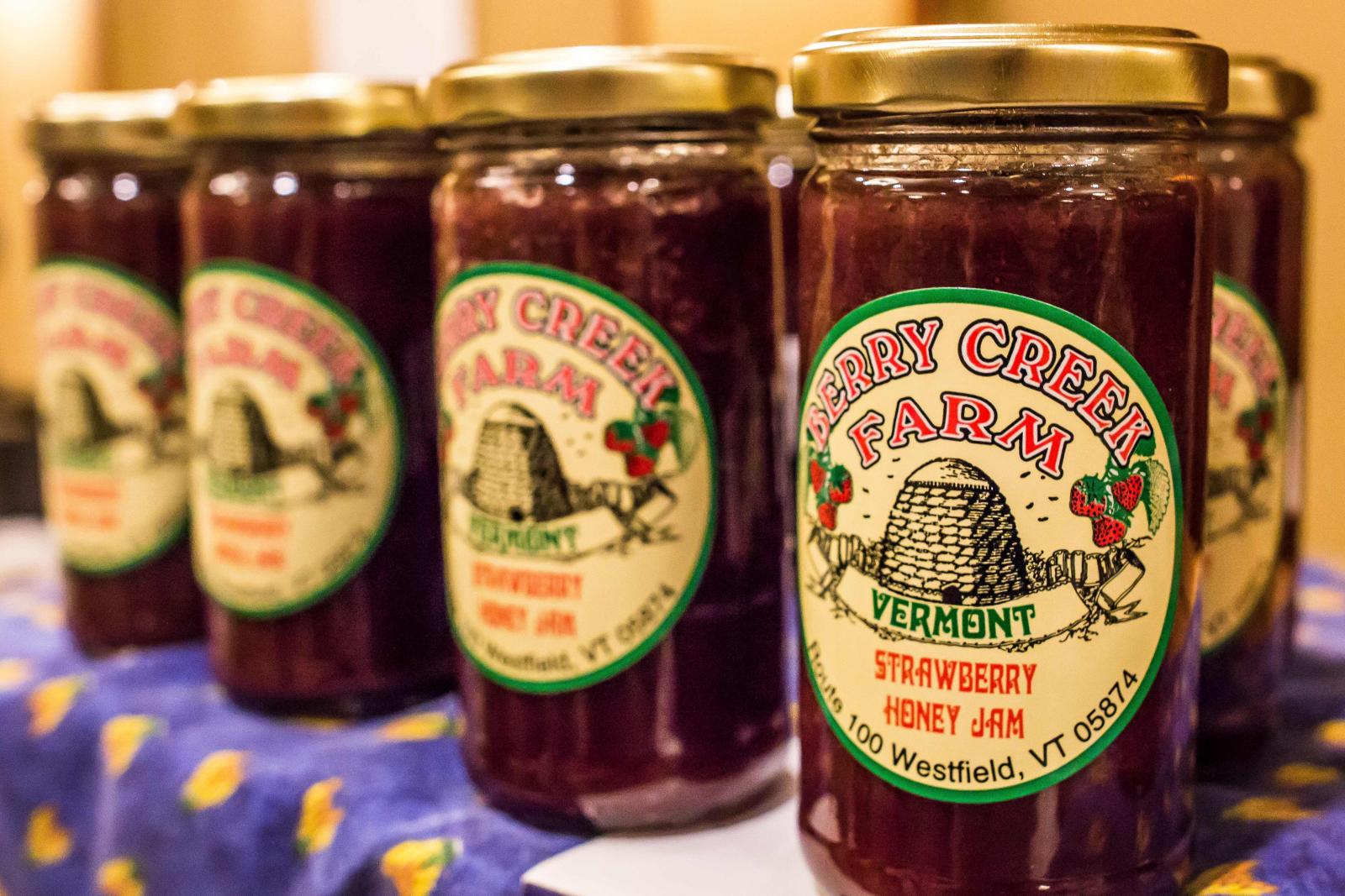 Jars of raspberry jam with colorful labels arranged in a row.