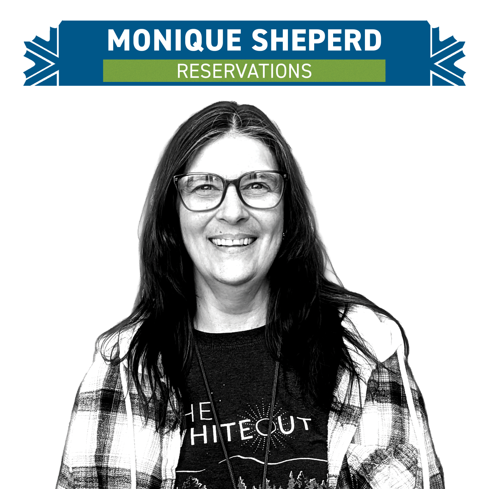 Smiling woman with glasses, wearing a plaid shirt and t-shirt.