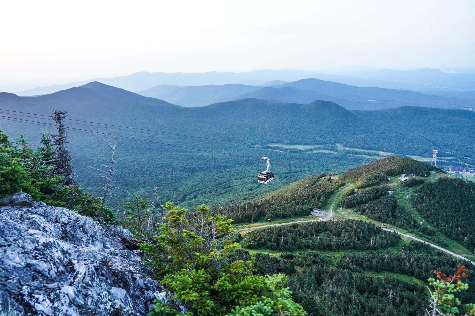 Mountain landscape with lush greenery and winding paths under a clear sky.