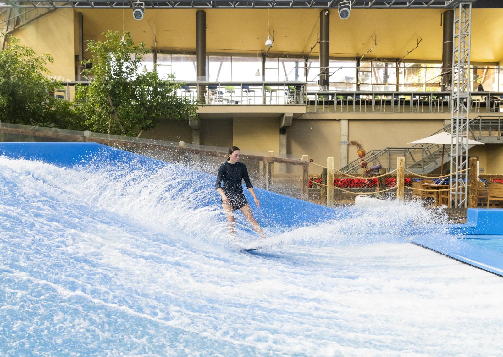 Indoor surfer riding artificial wave in a leisure center.