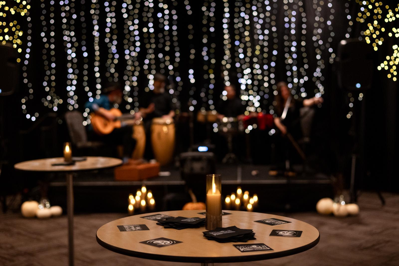 Cozy lounge with musicians on stage, warm lighting, and decorative candles.