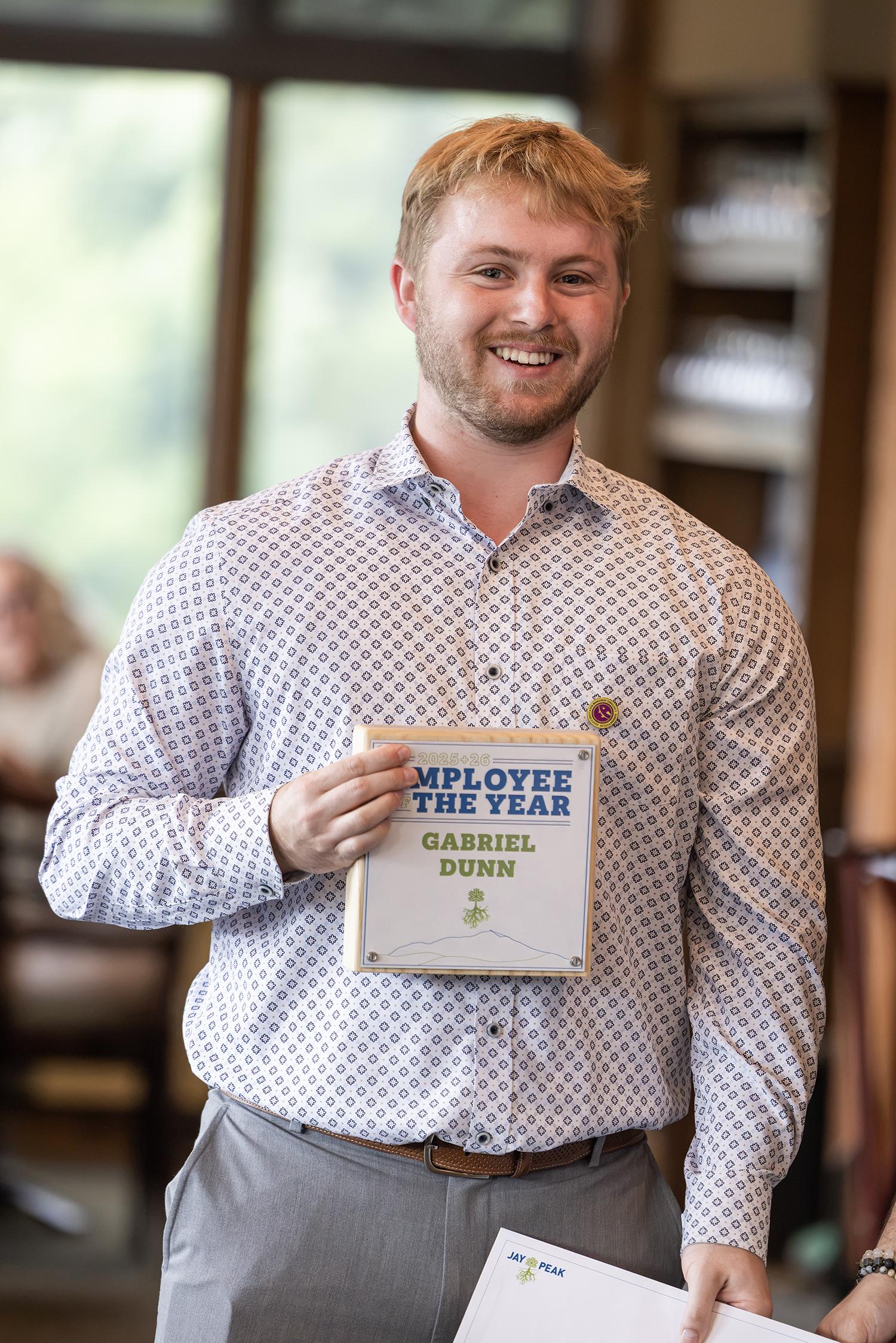Smiling man holding a certificate while standing indoors.