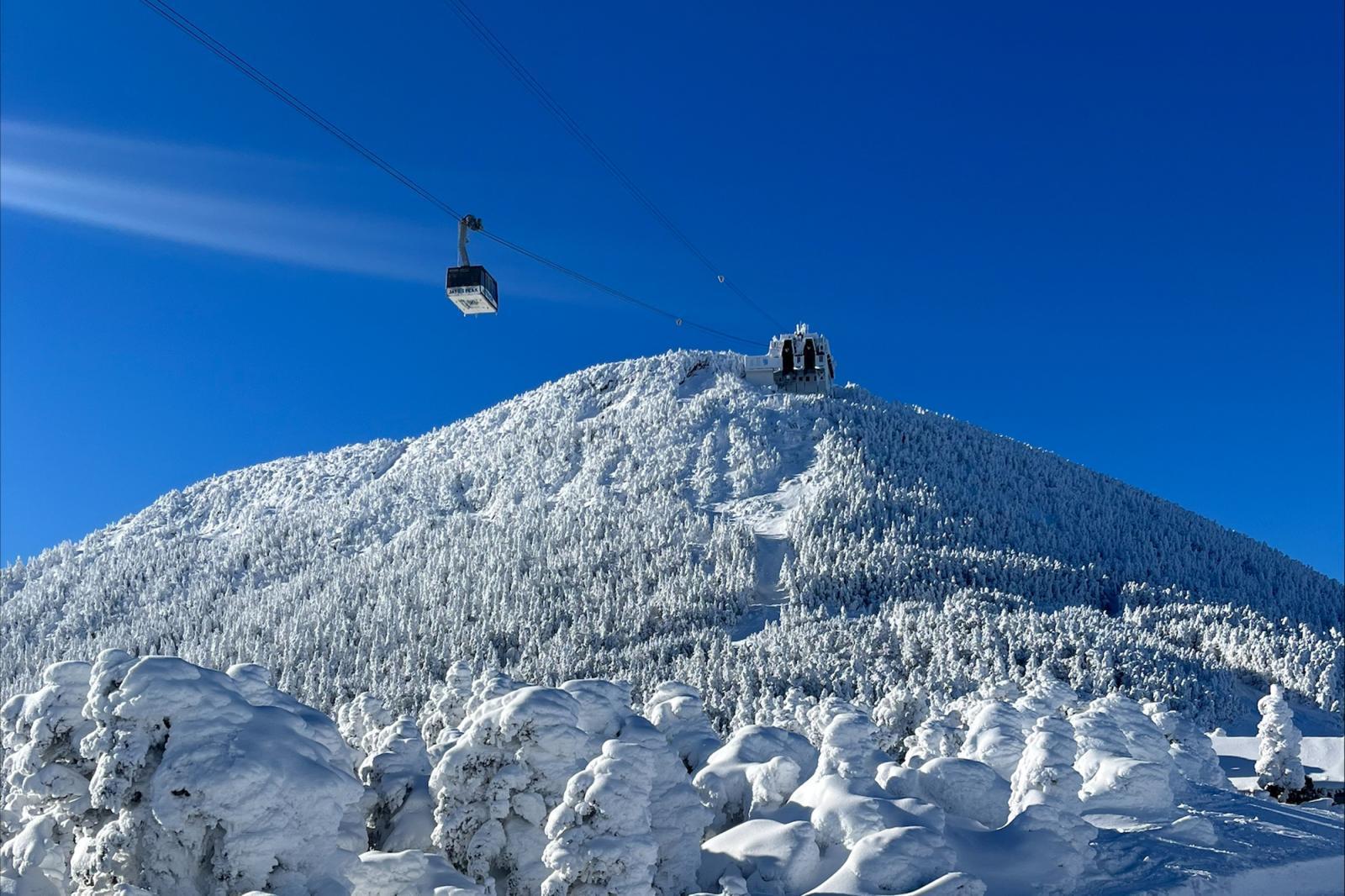 Snowy mountain with ski lift under clear blue sky.