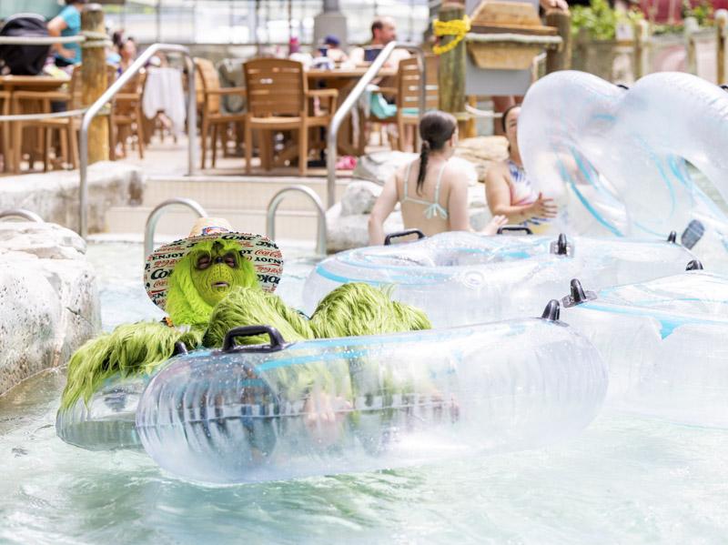 Child in a pool with a green inflatable crocodile and clear floaties