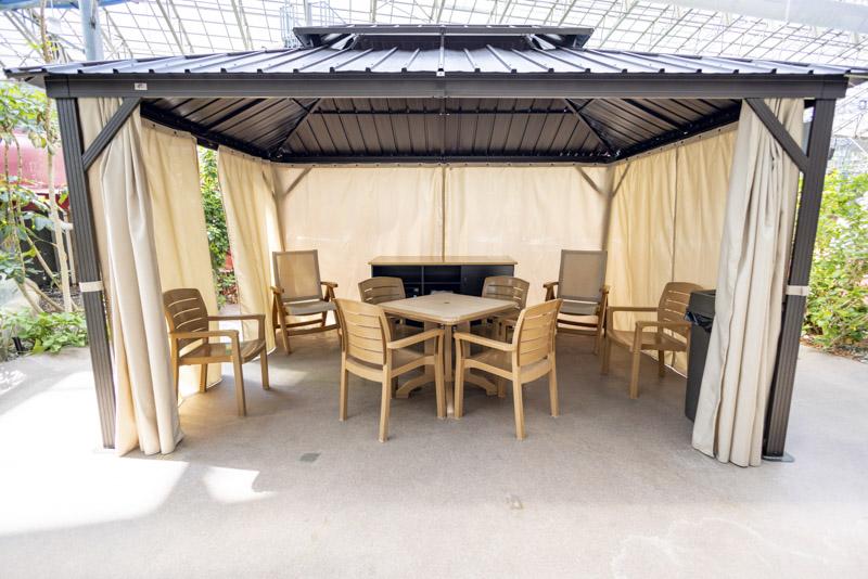 Open-sided bamboo patio gazebo with table and chairs beneath a corrugated roof